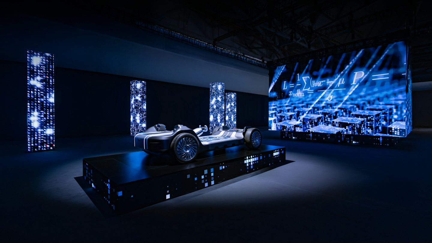 A futuristic vehicle chassis sits on a glowing digital platform.